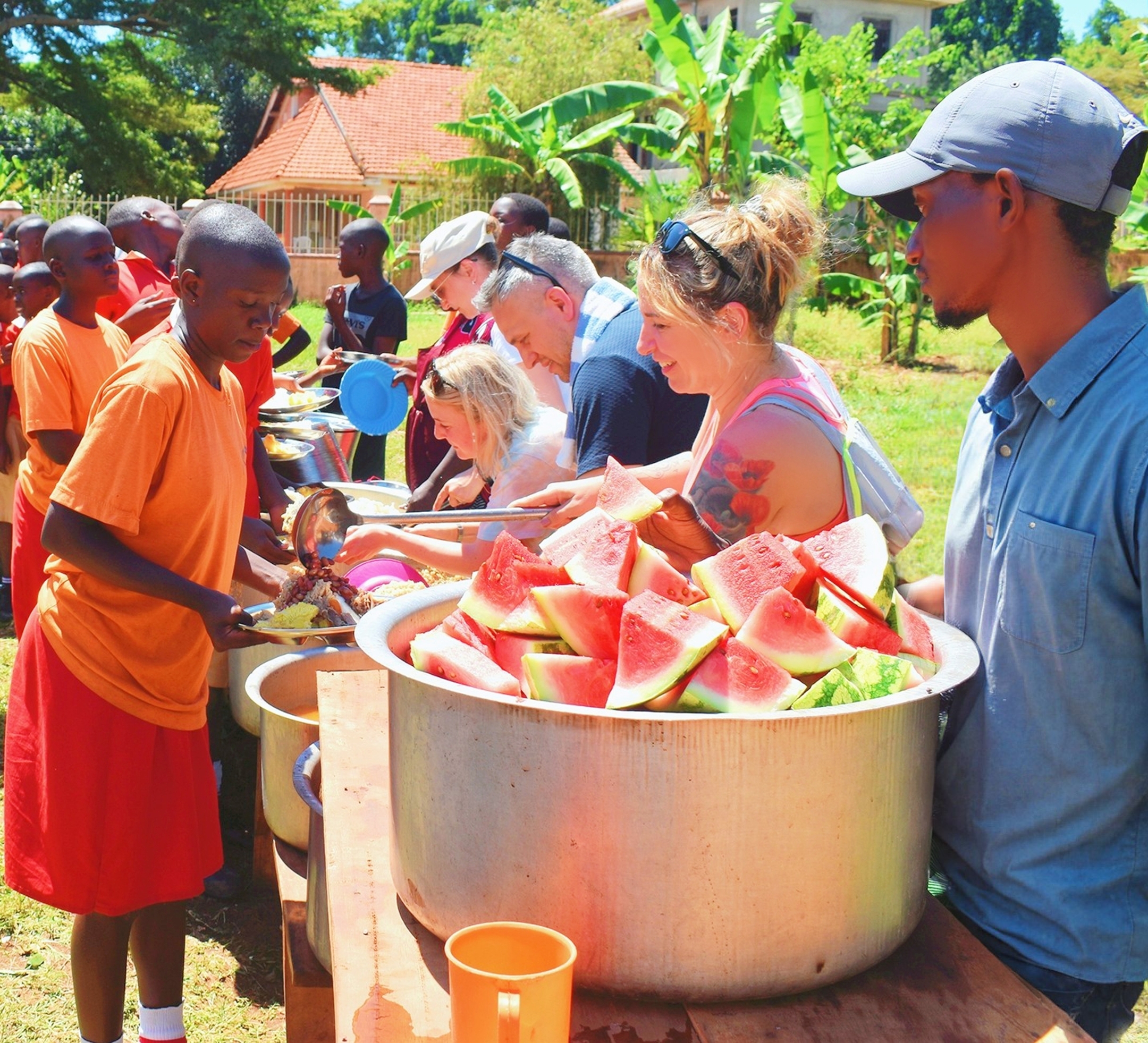 Volunteers serving watermelon to children